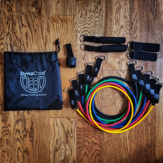 Fitness training system, resistance bands and attachments, with a drawstring bag on a wooden floor.